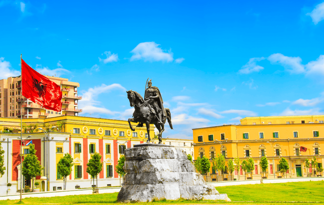 Skanderbeg Square in Tirana, Albania with iconic statue and national flag under a bright summer sky