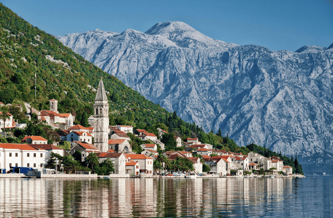 Scenic view of Kotor, Montenegro with medieval houses, church tower, and snowy mountains in the background – a must-visit stop on a Balkans winter trip