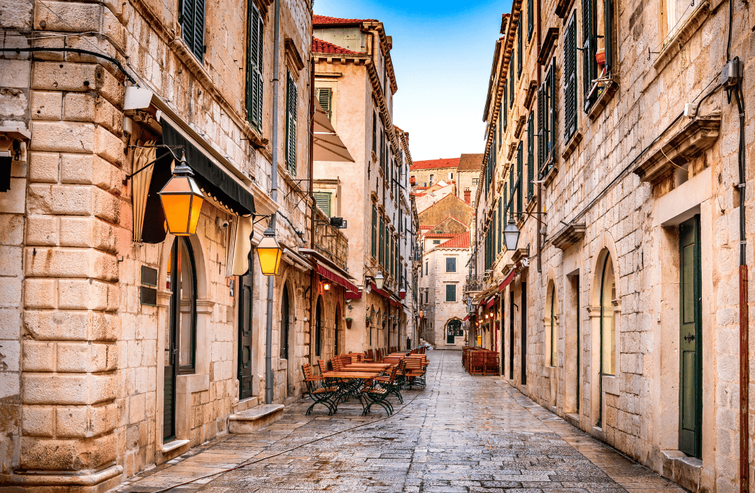 Charming cobblestone street with outdoor seating in Old Town Dubrovnik, Croatia – perfect for summer strolls and dining.