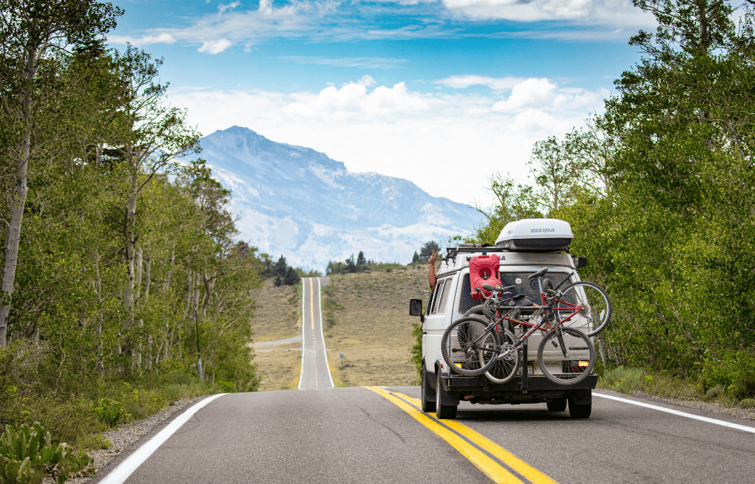 Camper van on scenic mountain road with bicycles, perfect for Father’s Day travel adventure in nature