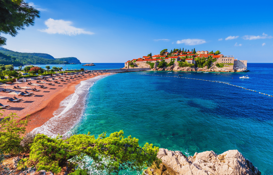 Stunning view of Sveti Stefan beach and islet in Montenegro with turquoise waters and sun loungers – affordable Balkan summer travel destination