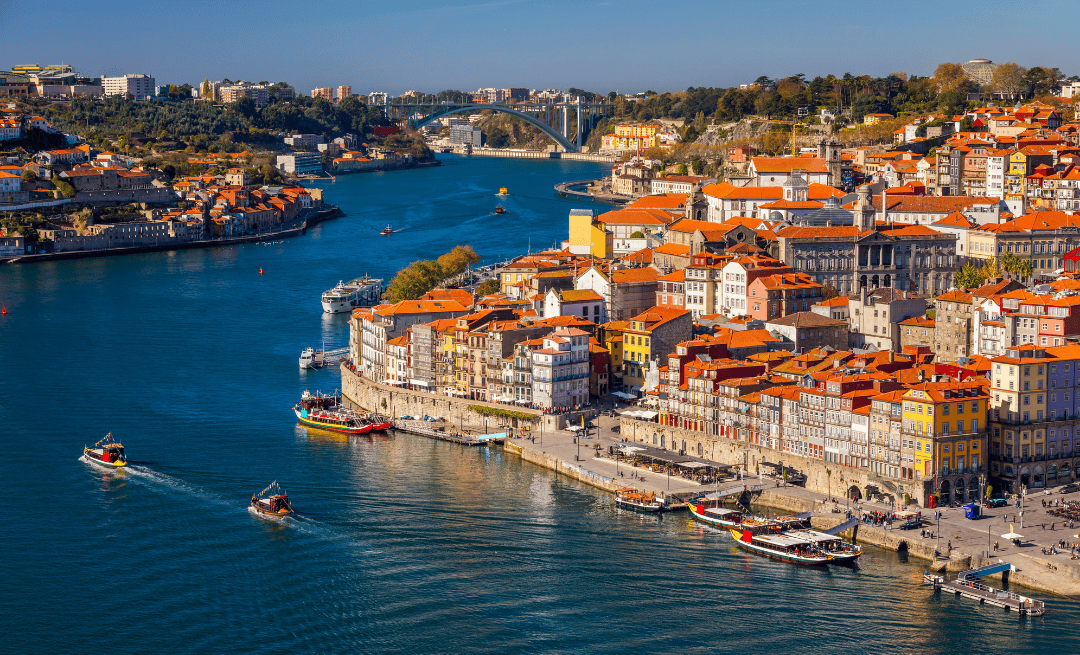 Vibrant riverside view of Porto, Portugal with traditional boats and colorful architecture in July