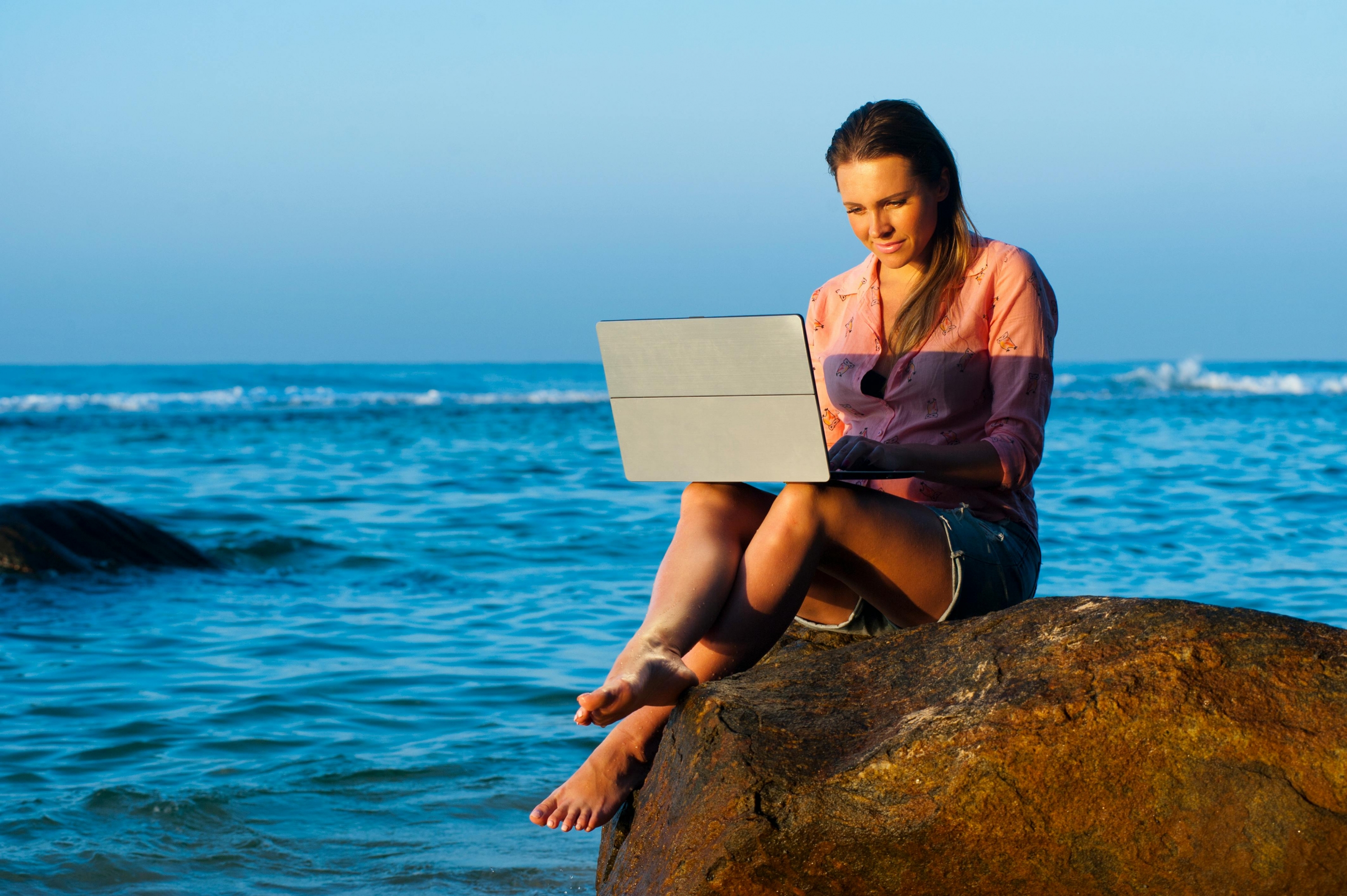 a woman using computer near seaside