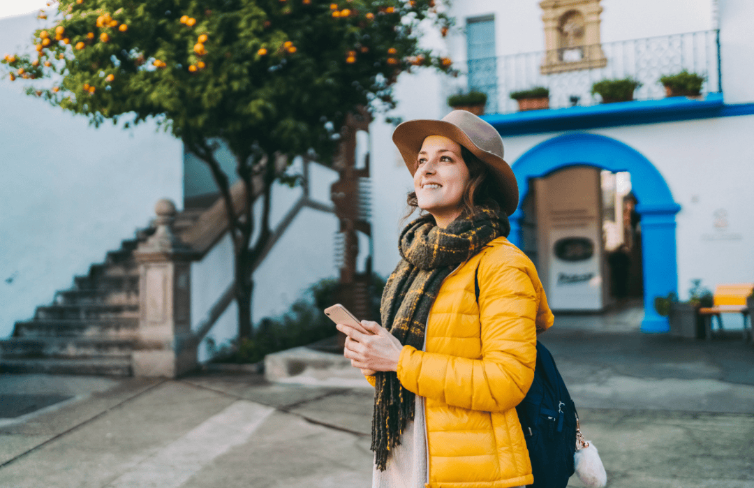 Female solo traveler using smartphone while exploring a charming European village in September