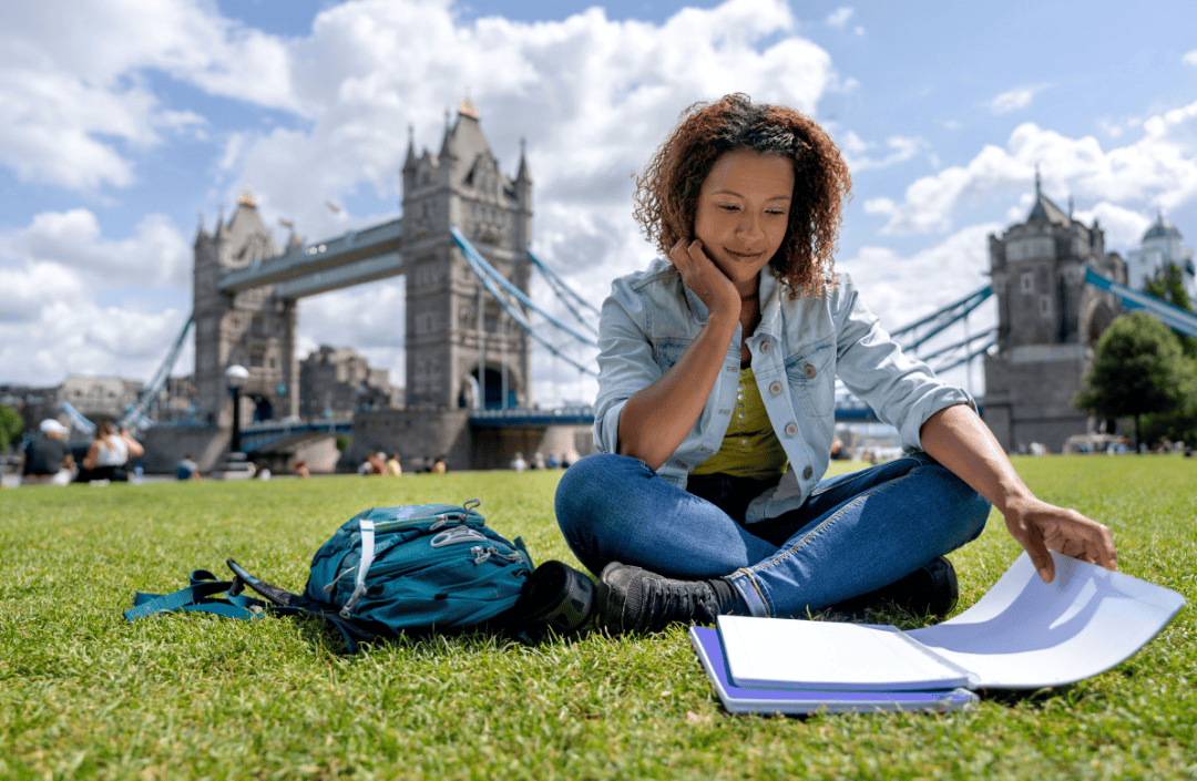 GCC student studying abroad in London near Tower Bridge with backpack and notebook