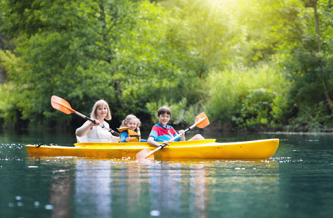 Happy family kayaking together at a nature-focused summer camp in Europe – perfect outdoor activity for kids and parents